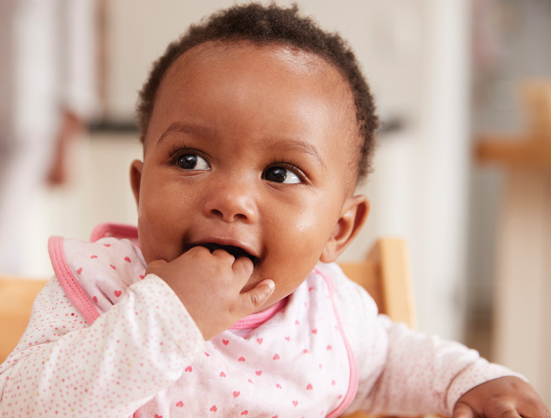 Cute Baby Girl Wearing Bib Sitting In High Chair