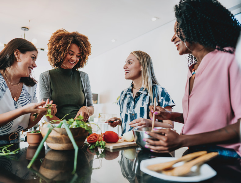 Group of female friends preparing vegan lunch at home together