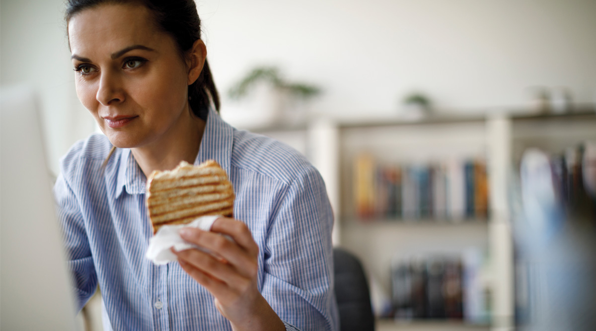 Woman eating lunch while working from home.
