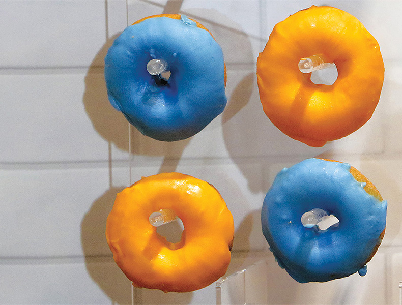 2 blue doughnuts and 2 orange doughnuts hanging on a wall
