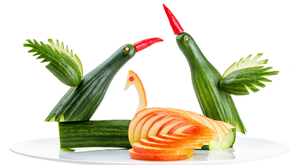 Cucumbers shaped as birds with red pepper beaks and an apple shaped as a swan.