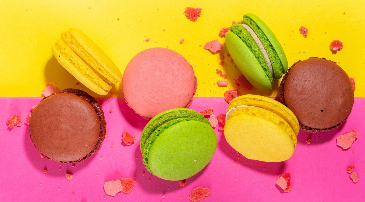 Colorful macarons against a pink and yellow background.